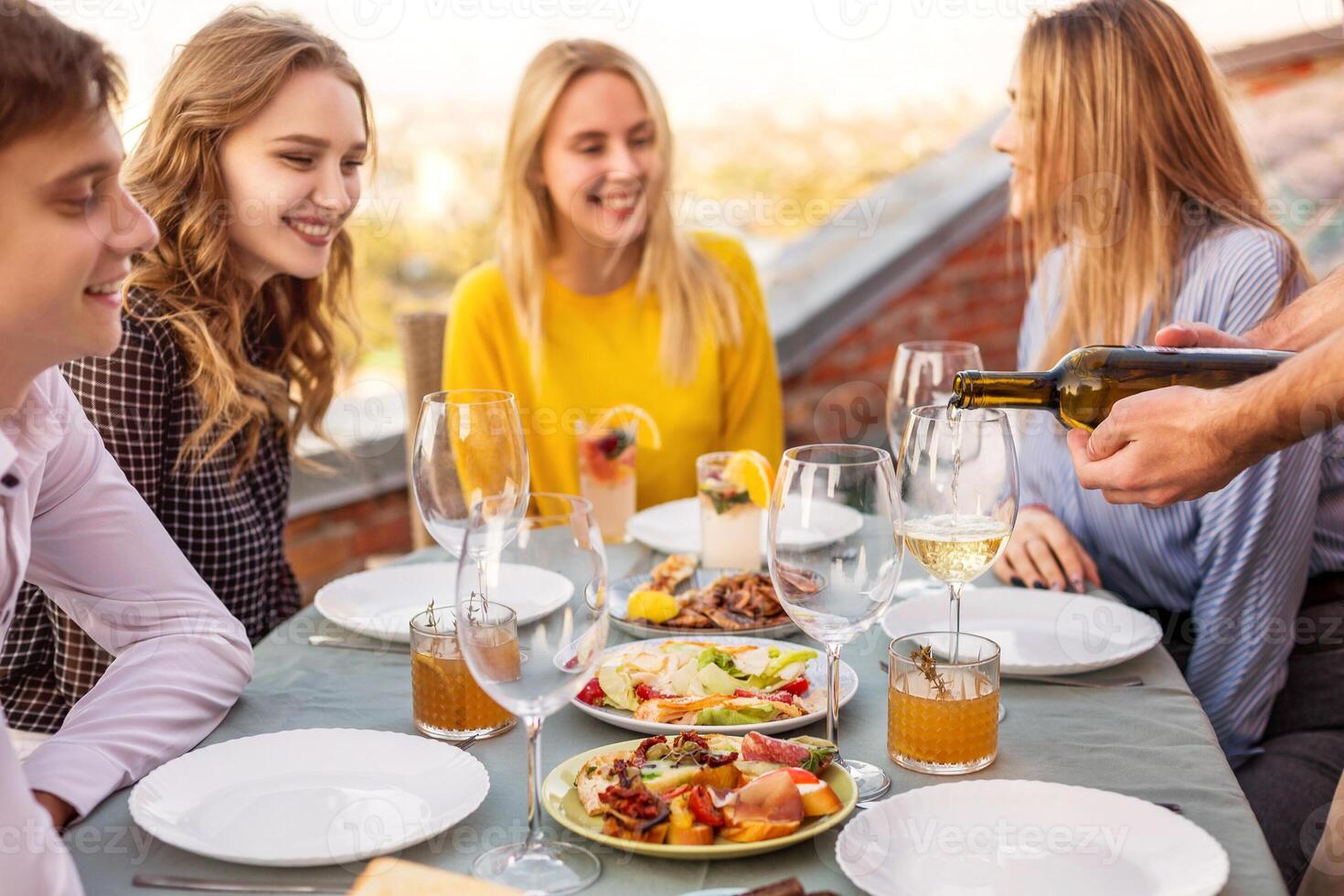 Happy friends waiting for waiter to pour wine photo