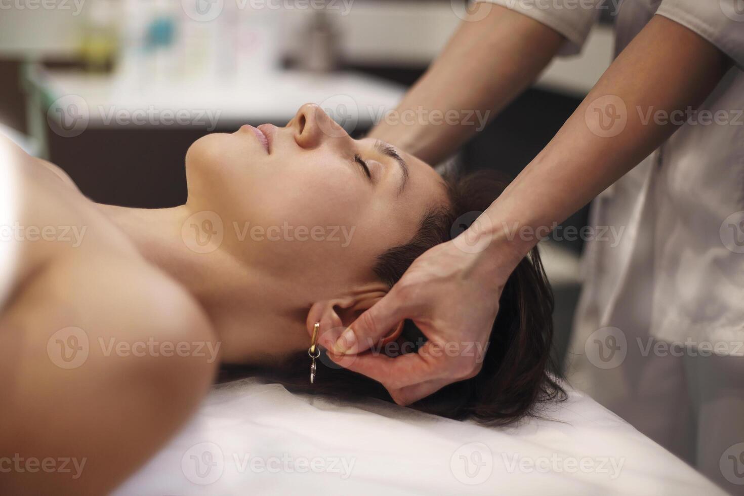 Crop massage therapist massaging face of client photo