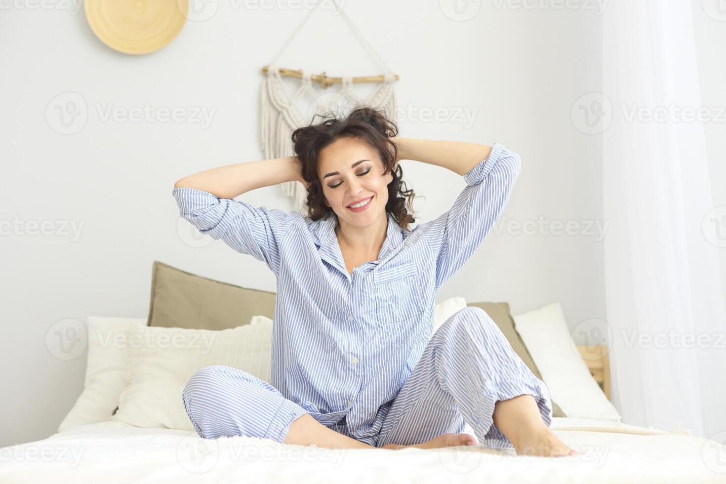 Smiling brunette woman in pajamas resting on bed photo