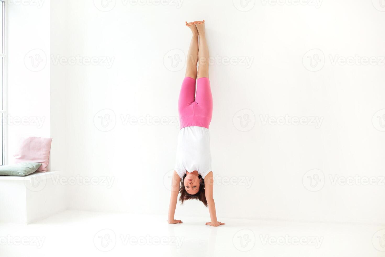 Slim woman doing balancing handstand asana photo
