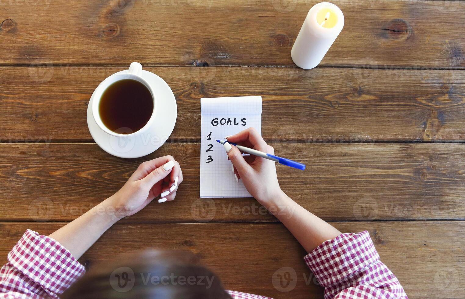 Crop woman writing goals in notepad photo