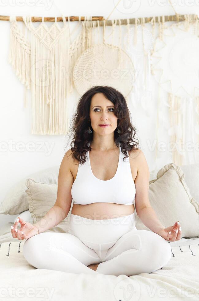 Beautiful brunette pregnant woman stretching and practicing yoga photo