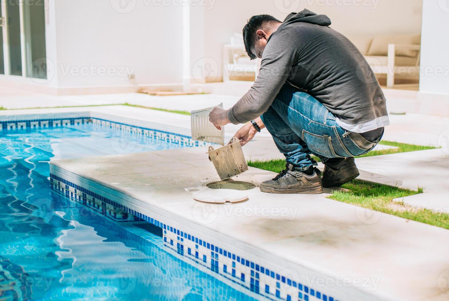Man cleaning swimming pool garbage filter. Worker removing trash from swimming pool filter basket photo