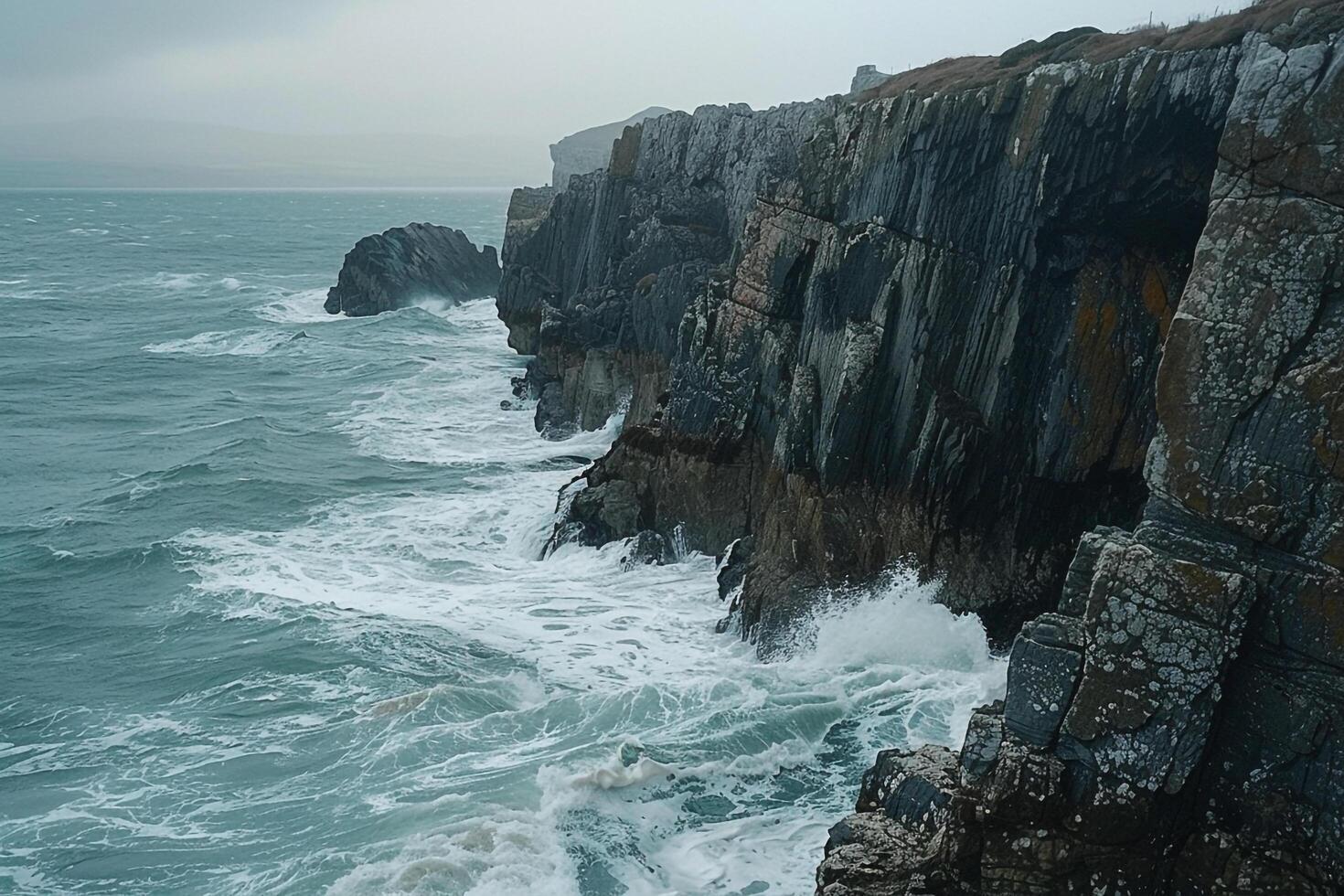 Patterns of waves crashing on rocky shoreline creating foam patterns against the rugged cliffs   nature background photo