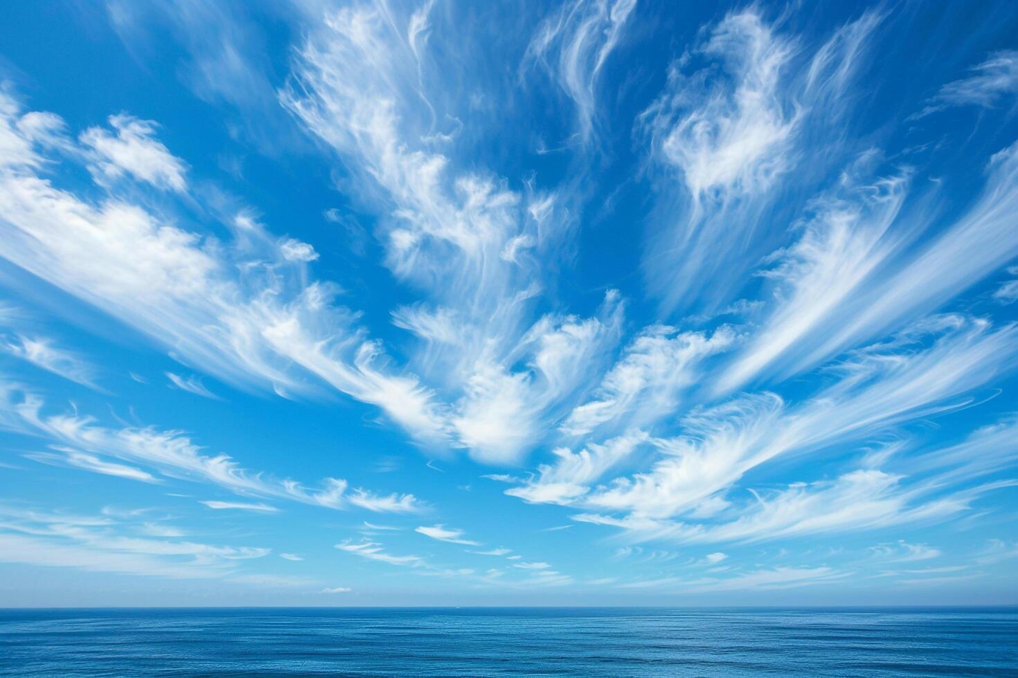 Nature Background of Wispy Cirrus Clouds in a Blue Sky Over the Ocean photo
