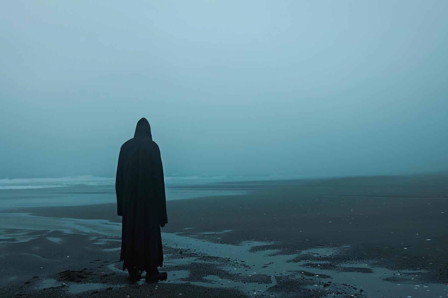 Hooded Figure Alone on Misty Beach at Dawn Mysterious and Atmospheric Coastal photo
