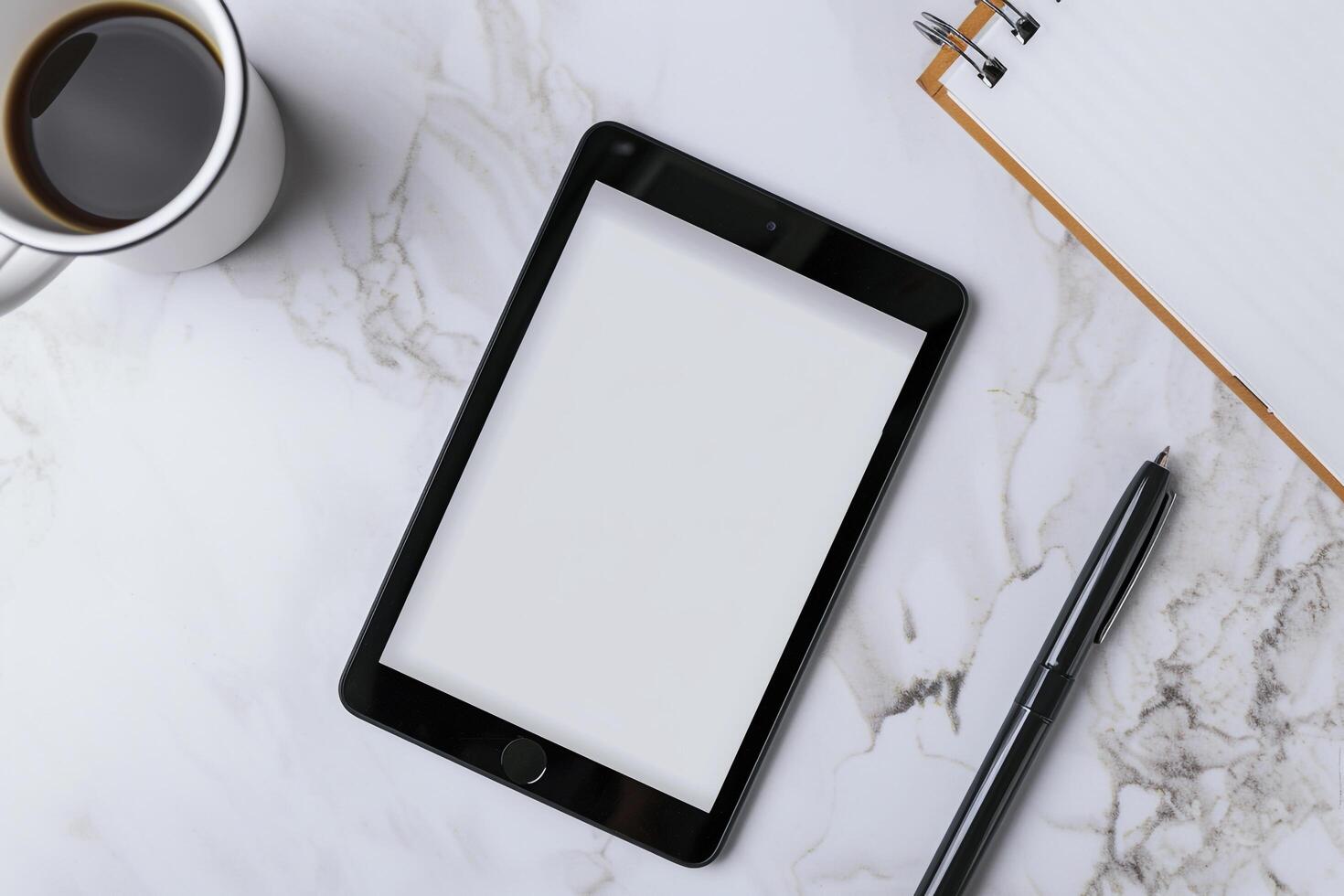 Tablet on Desk with Pen and Notepad on Wooden Surface photo
