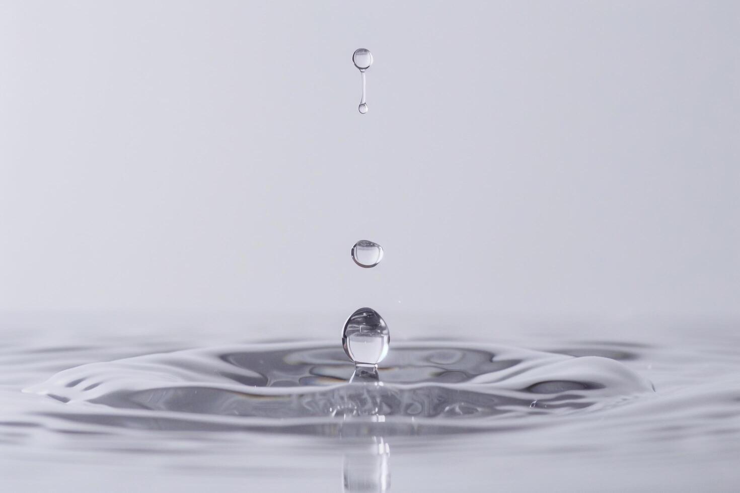 Single Water Droplet Creating Ripples in a Tranquil Pool of Water photo