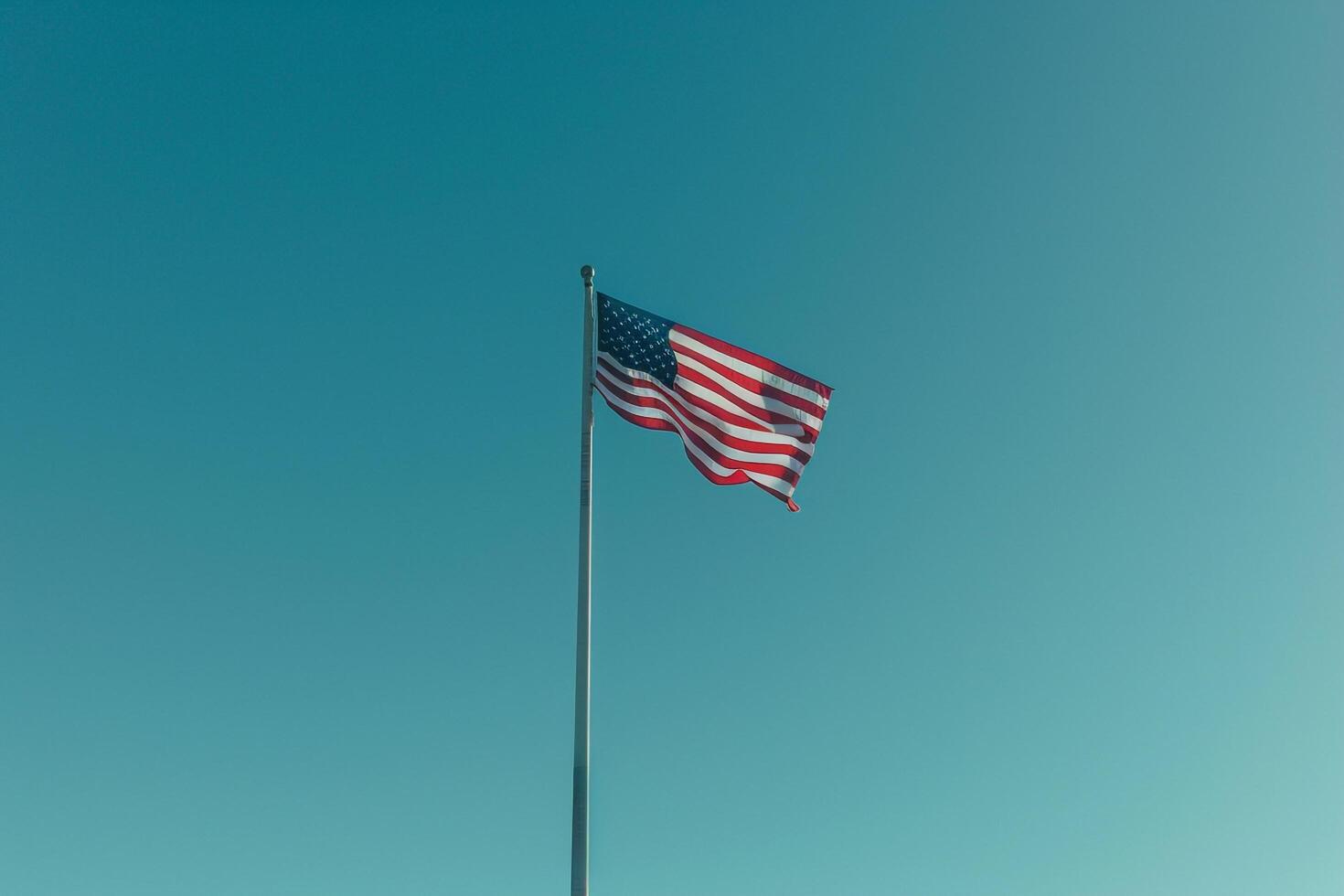 American Flag Waving in the Breeze Against a Blue Sky Emphasizing National Pride and Unity photo
