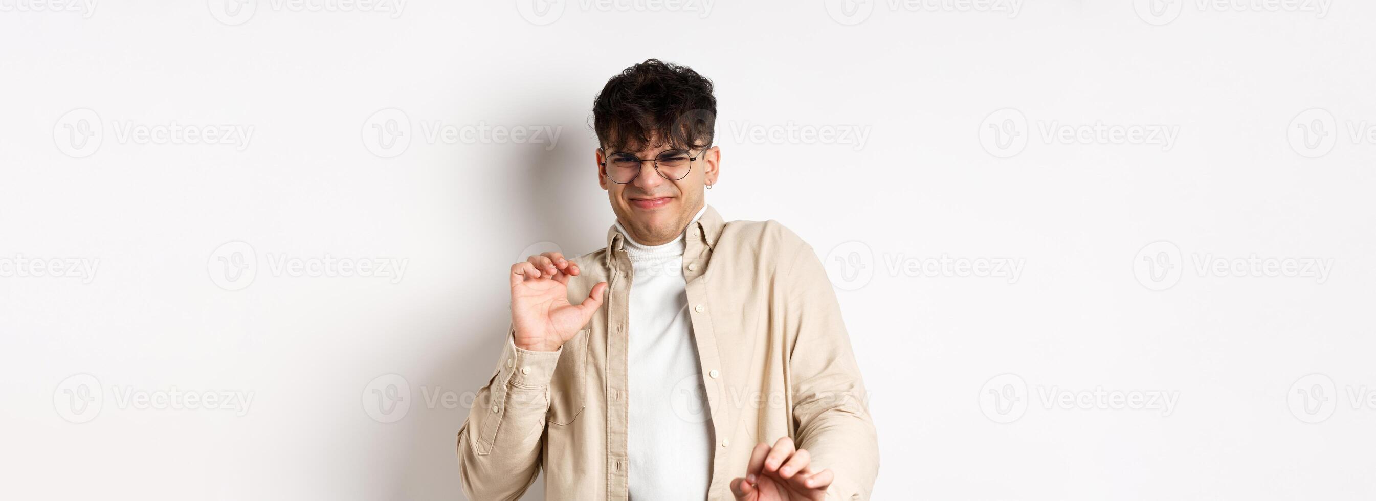Disgusted guy grimacing and jumping away from something nasty, stare with aversion and dislike, rejecting bad offer, standing on white background photo