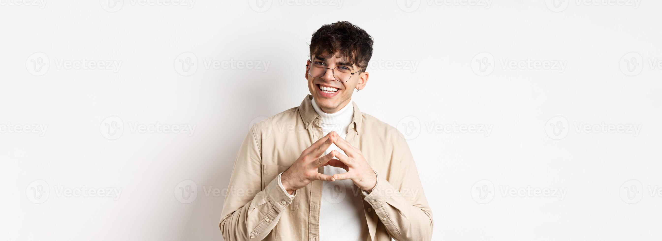 Portrait of hipster guy in glasses with white smile, steeple fingers as having plan, scheming something interesting, standing cunning on white background photo