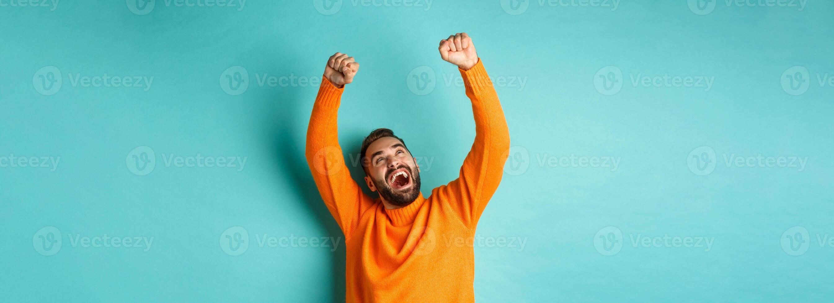 Happy man triumphing and feeling rejoice of winning, celebrating victory, standing over light blue background photo
