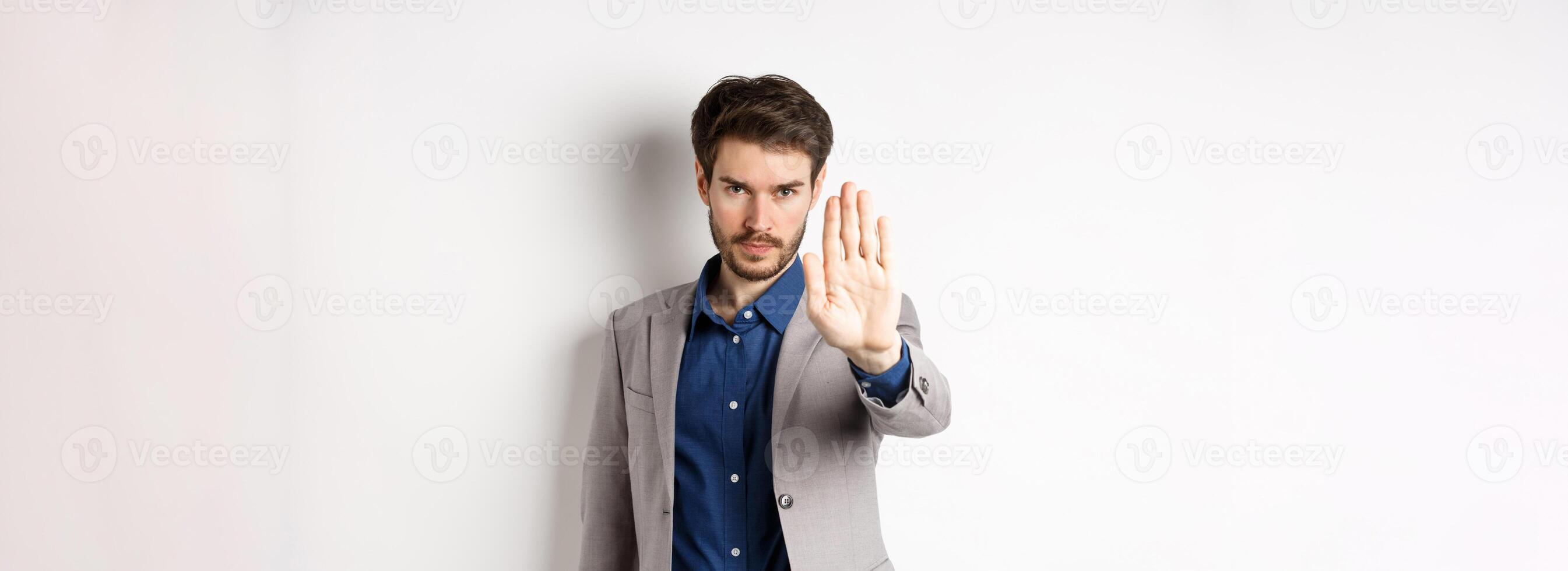 Hold right there. Serious businessman in suit stretch out hand and tell to stop, frowning and look confident, disapprove action, prohibit something bad, standing on white background photo