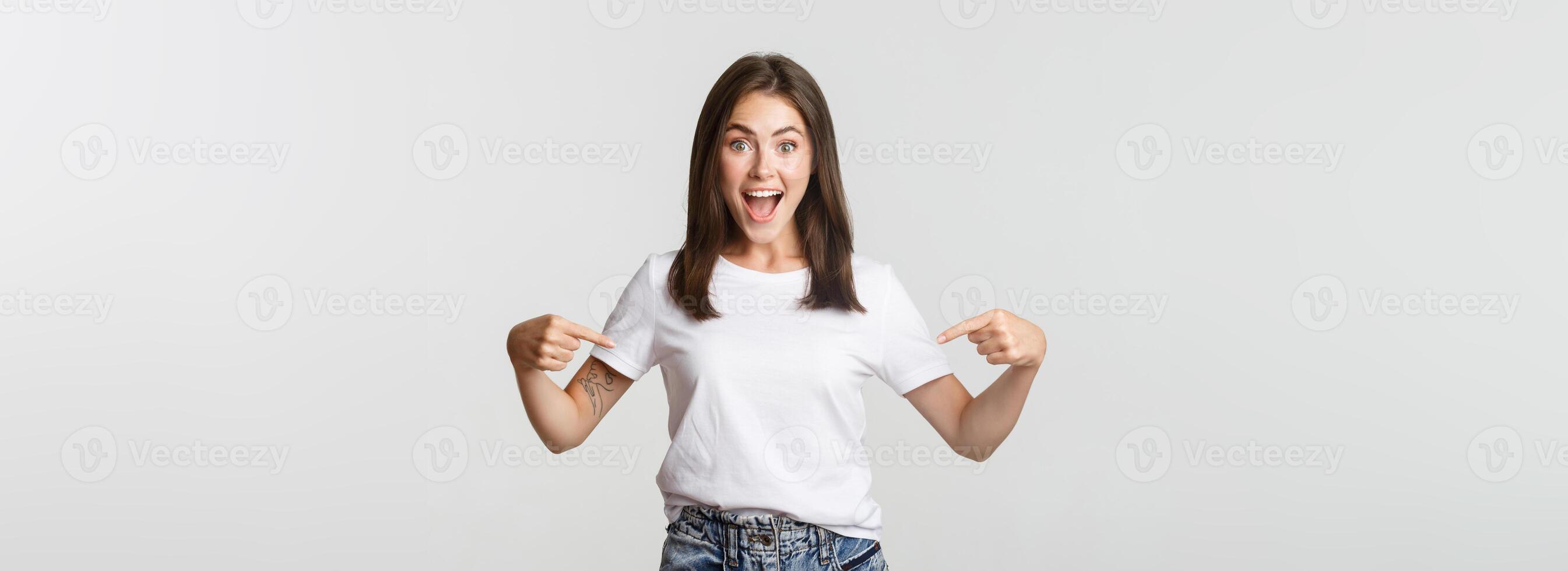 Excited happy brunette girl smiling, pointing fingers at logo, showing banner photo