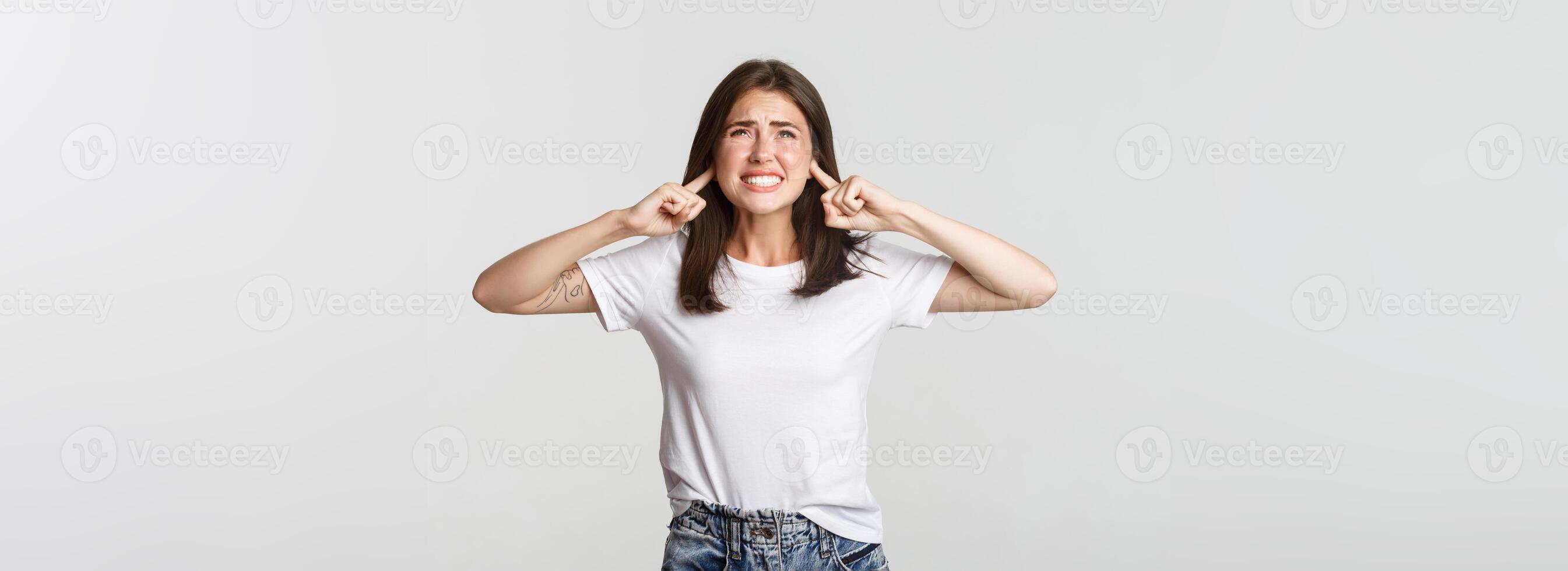Annoyed and bothered girl shut ears and complaining at loud awful noise photo