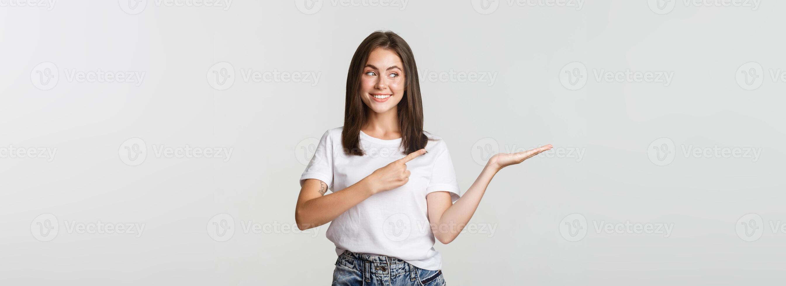 Attractive young woman pointing finger at something she holding on hand photo