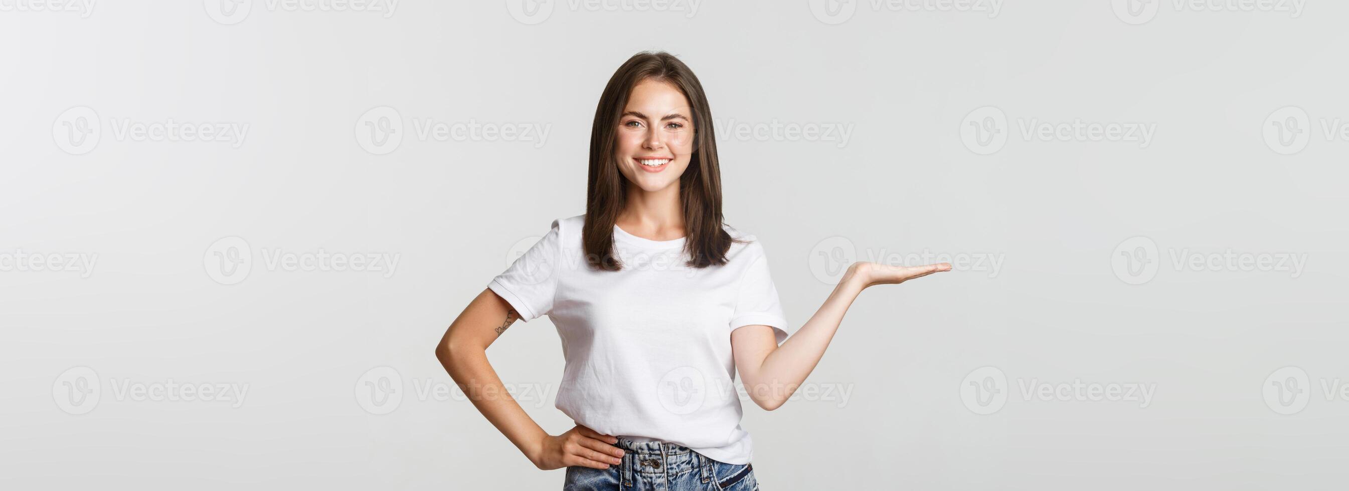 Beautiful smiling girl introduce something, holding on hand photo