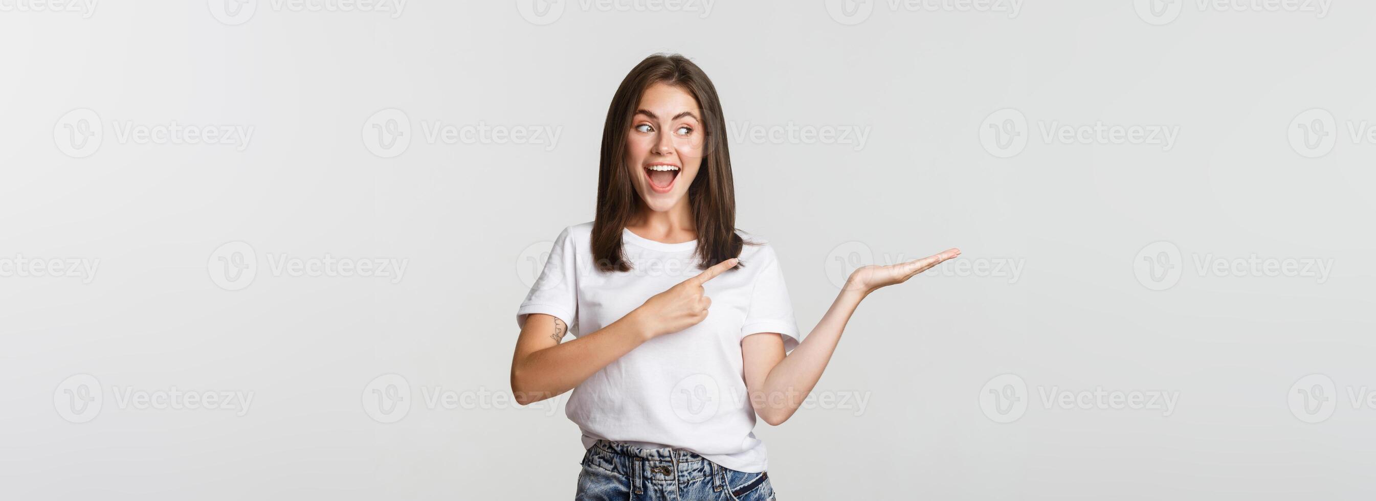 Attractive young woman pointing finger at something she holding on hand photo