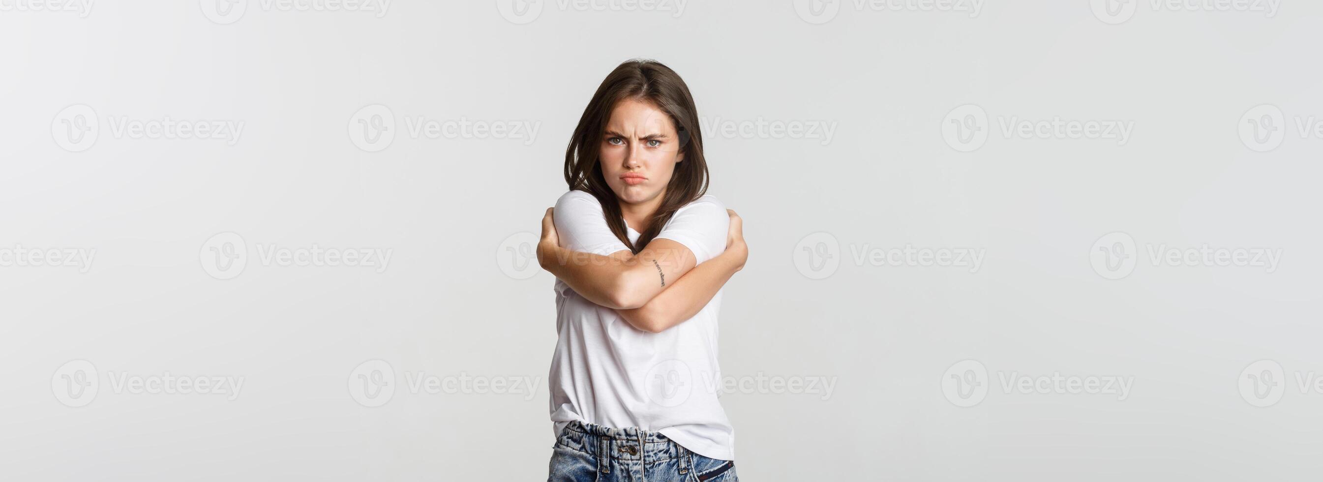 Offended sulking girl looking defensive and hugging herself photo