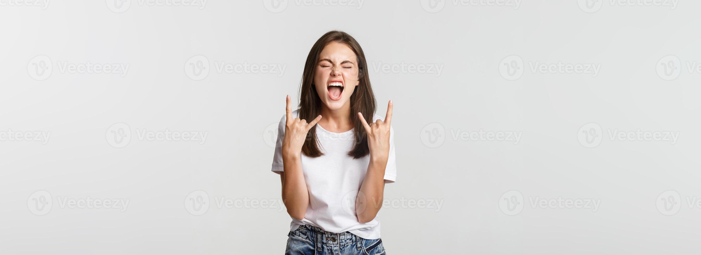 Joyful good-looking girl showing rock-on gesture and enjoying concert photo