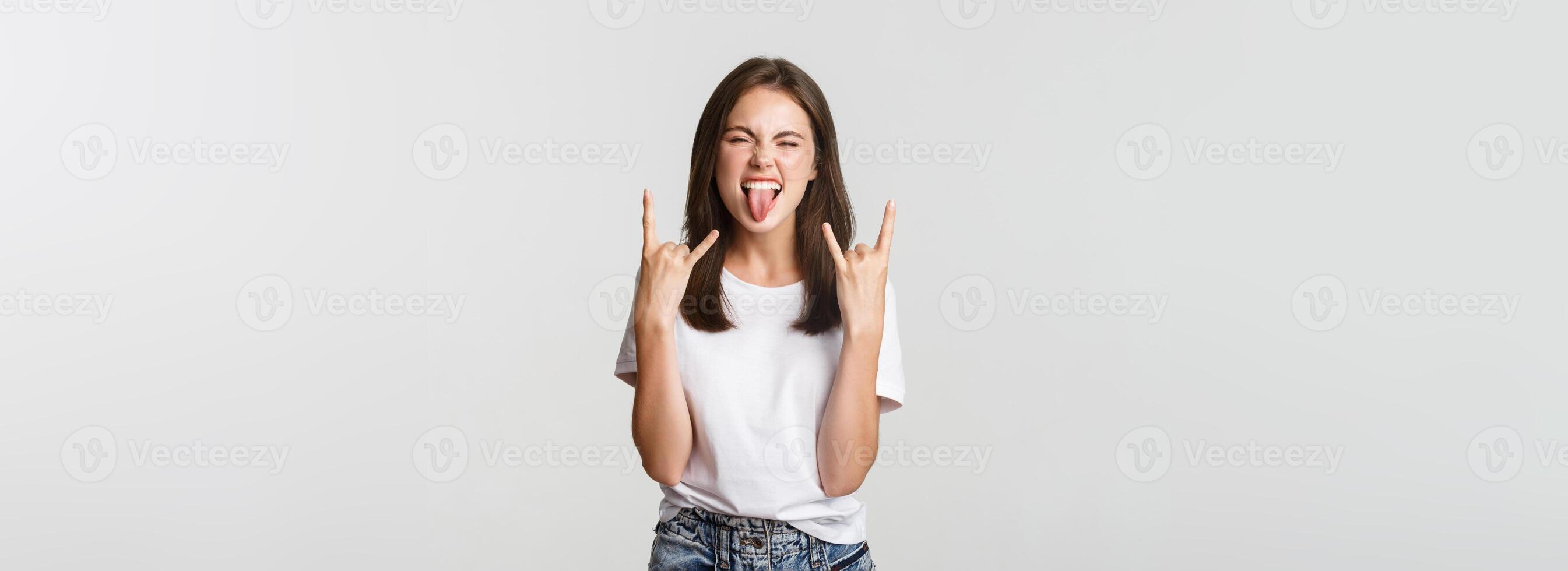 Joyful good-looking girl showing rock-on gesture and enjoying concert photo