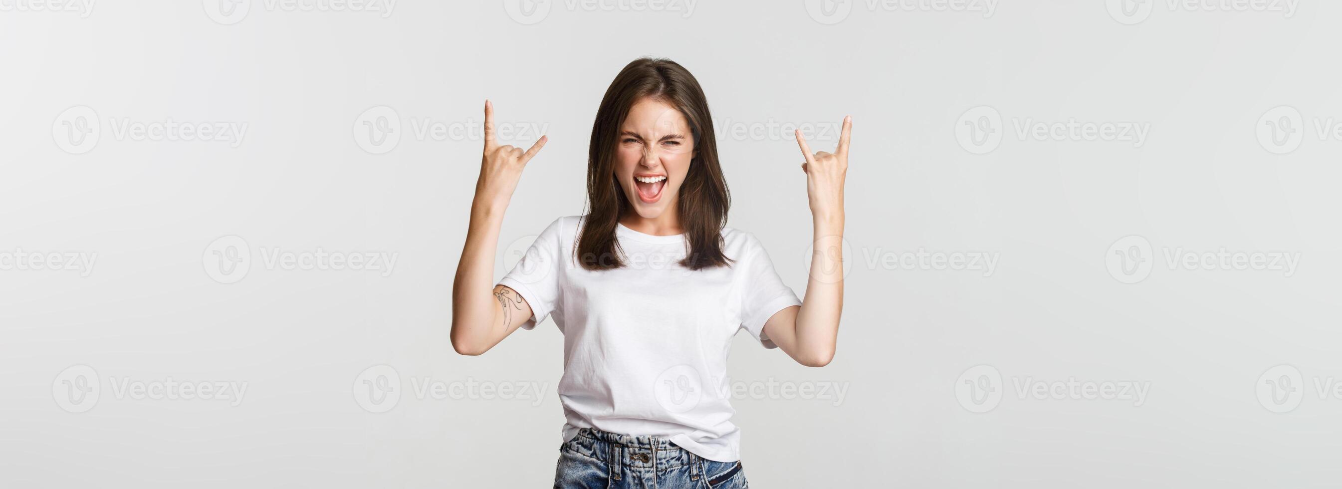 Joyful good-looking girl showing rock-on gesture and enjoying concert photo