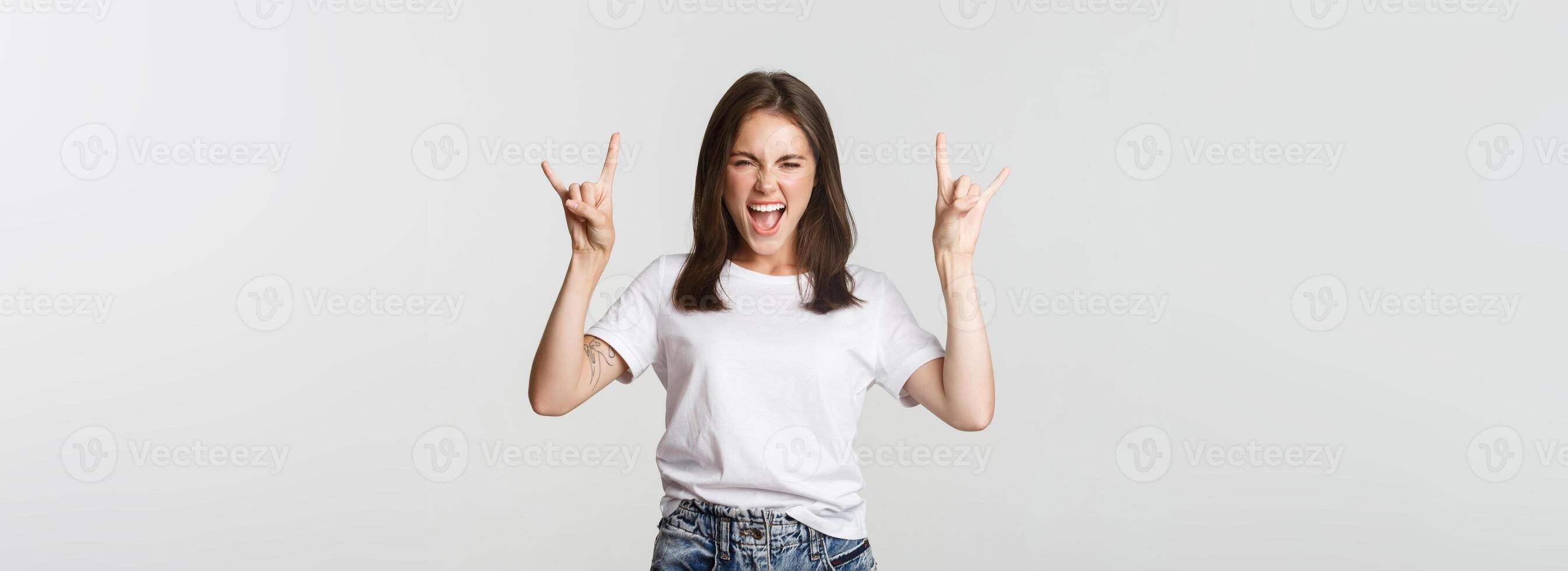 Joyful good-looking girl showing rock-on gesture and enjoying concert photo