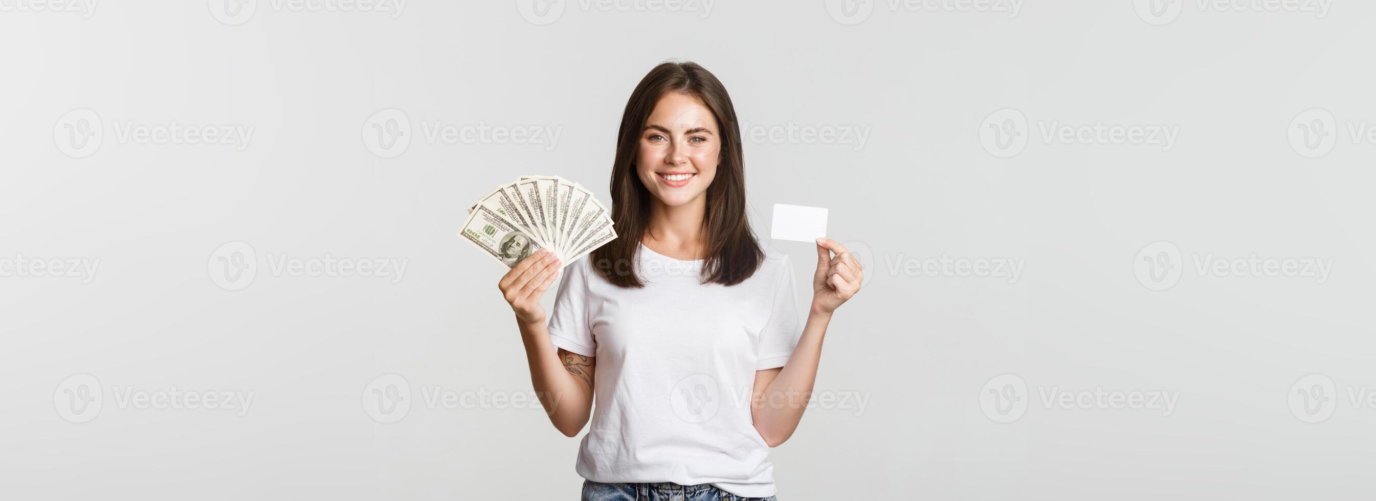 Portrait of excited smiling girl holding money and credit card, white background photo