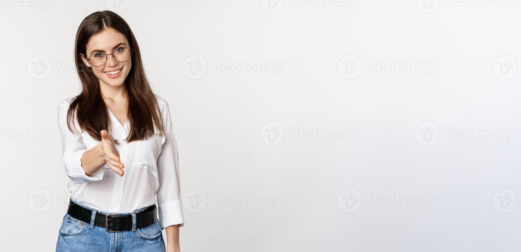 Corporate woman in office extending hand and smiling, handshake, greeting business partner, standing in glasses over white background photo
