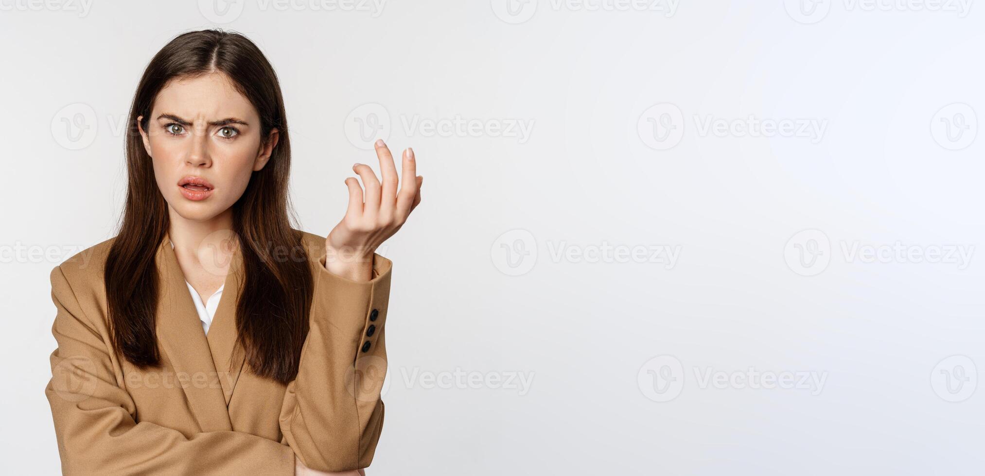 Portrait of confused businesswoman, staring puzzled and frustrated, cant understand smth, standing in suit over white background photo