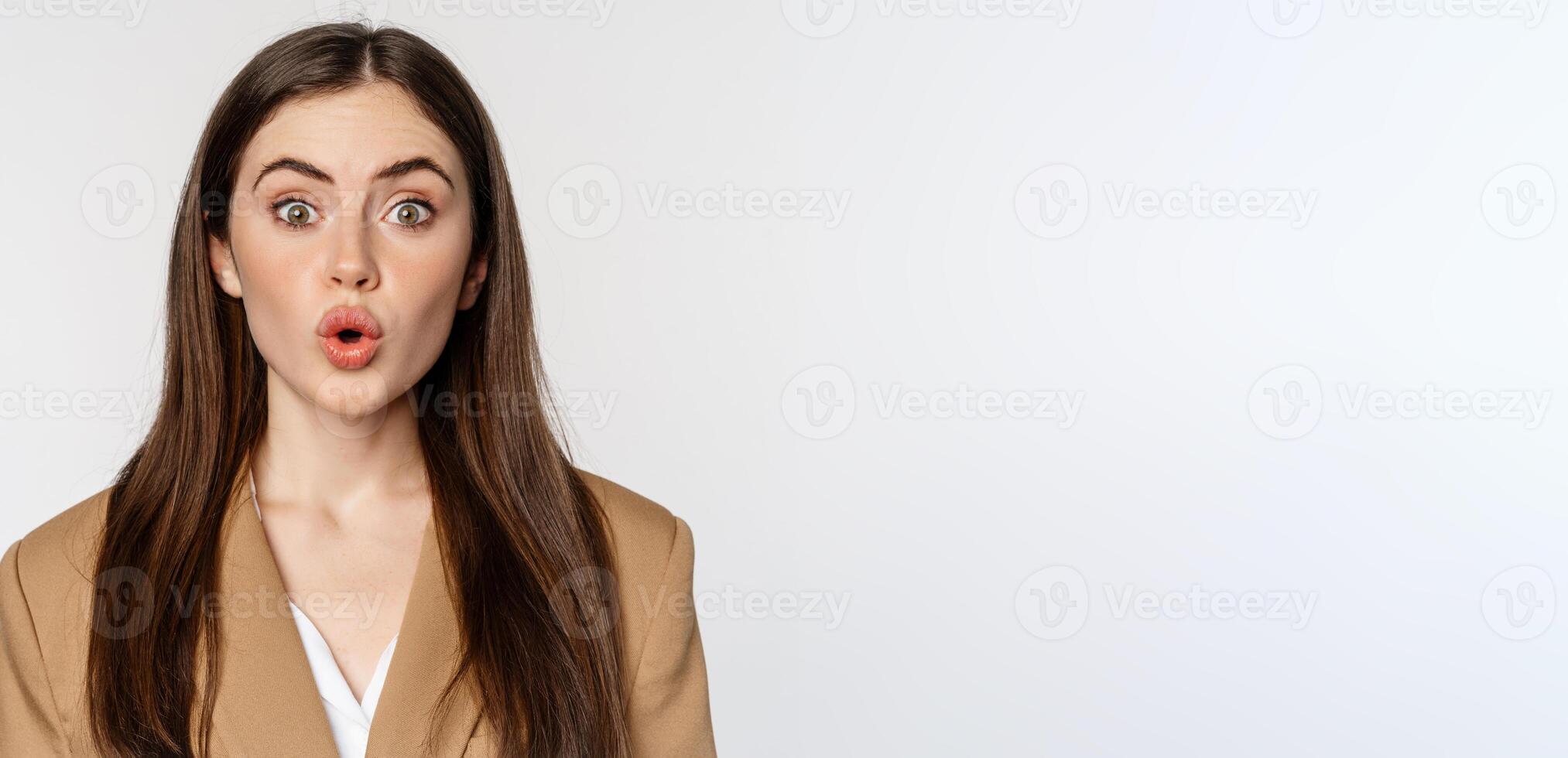 Close up portrait of surprised, amazed businesswoman, say wow, staring impressed at camera, fascinated face expression, white background photo
