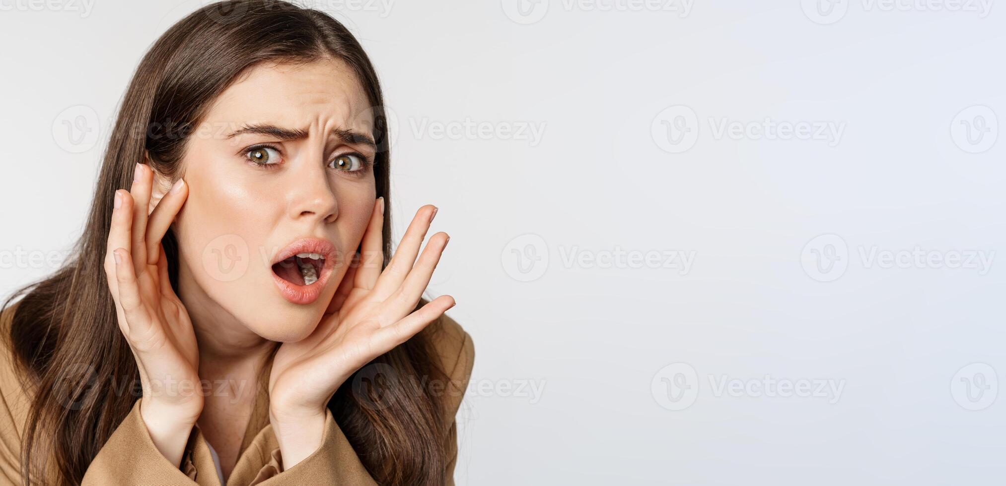 Image of sad girl looking in mirror and touching facial skin, shocked and frustrated over bad skin condition, standing over white background photo