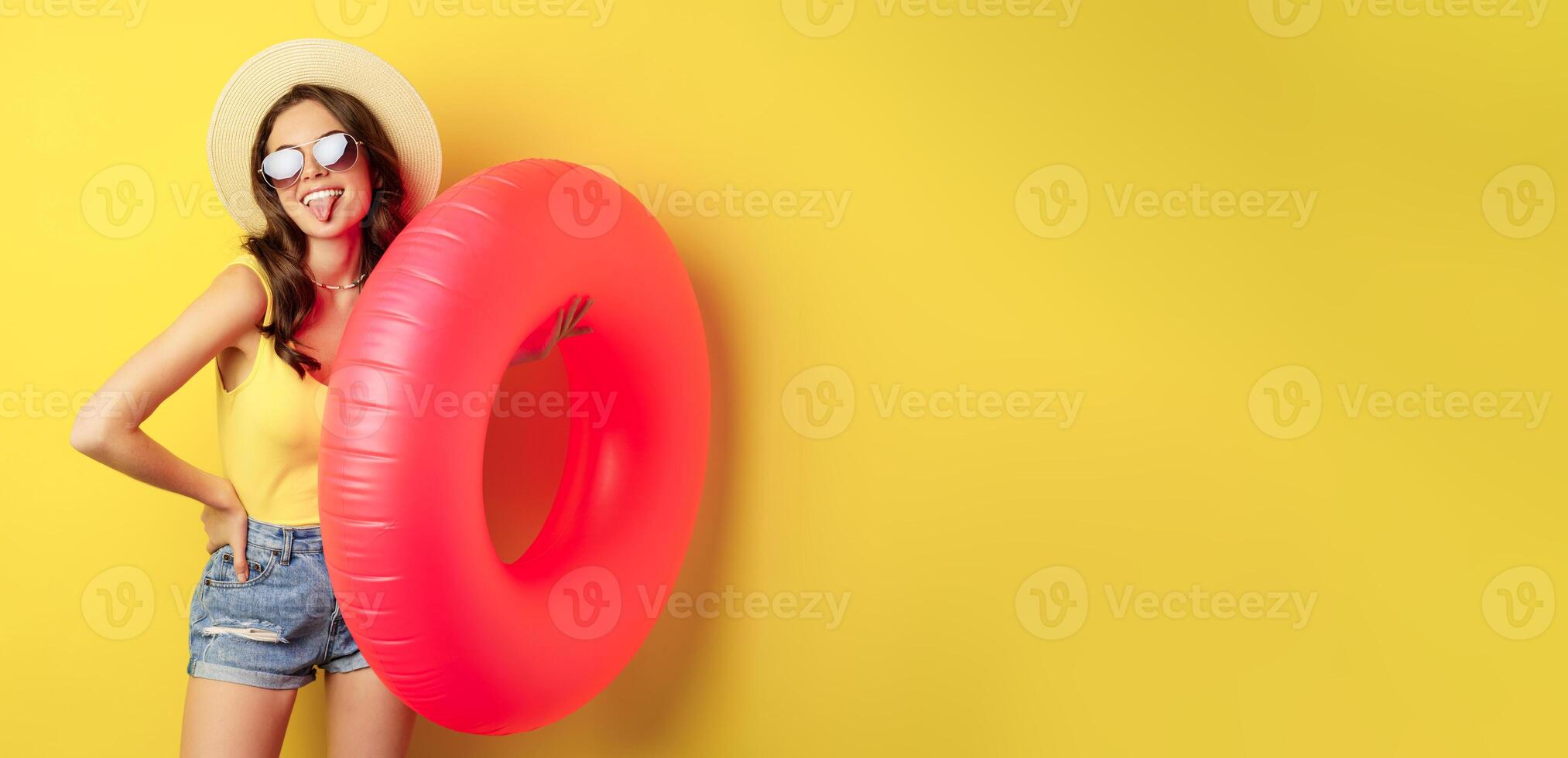 Stylish beach girl with swimming ring, laughing and smiling on summer vacation, sea trip, standing happy against yellow background photo