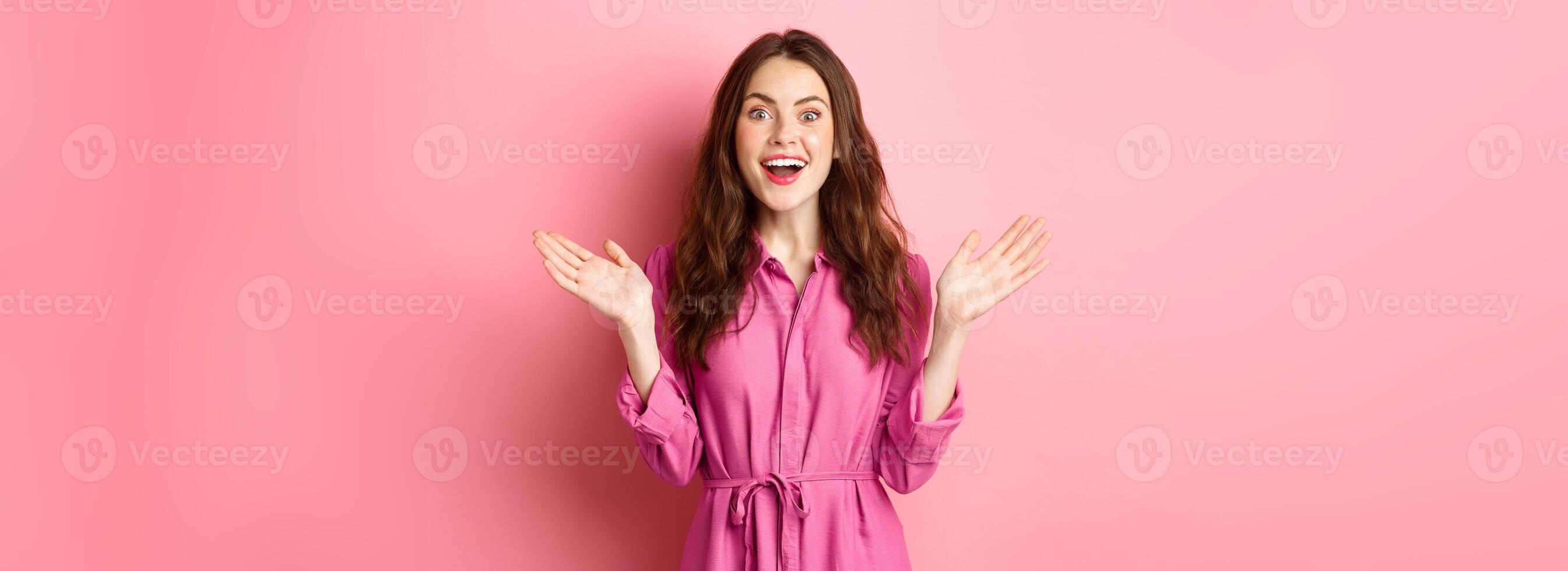 Cheerful attractive lady scream of joy and clap hands, looking at camera, hear great news, rejoicing, standing over pink background photo