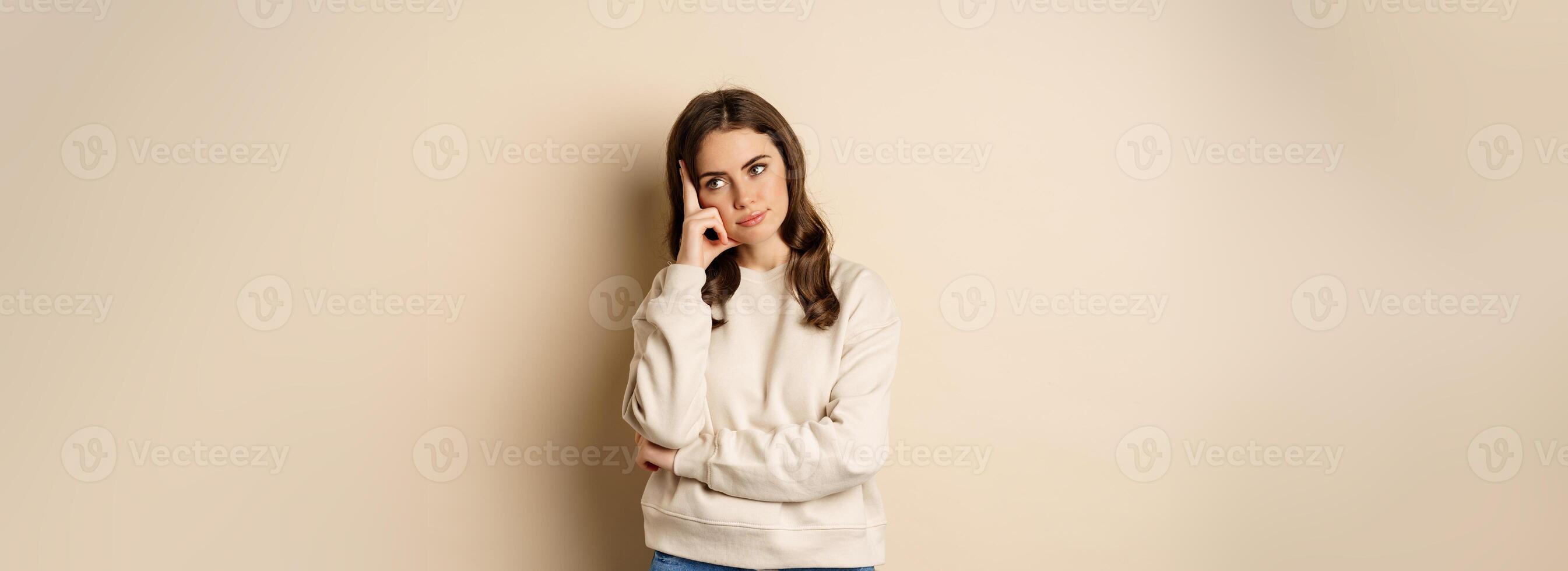 Annoyed woman, roll eyes and looking unamused, bothered and bored, standing over beige background photo