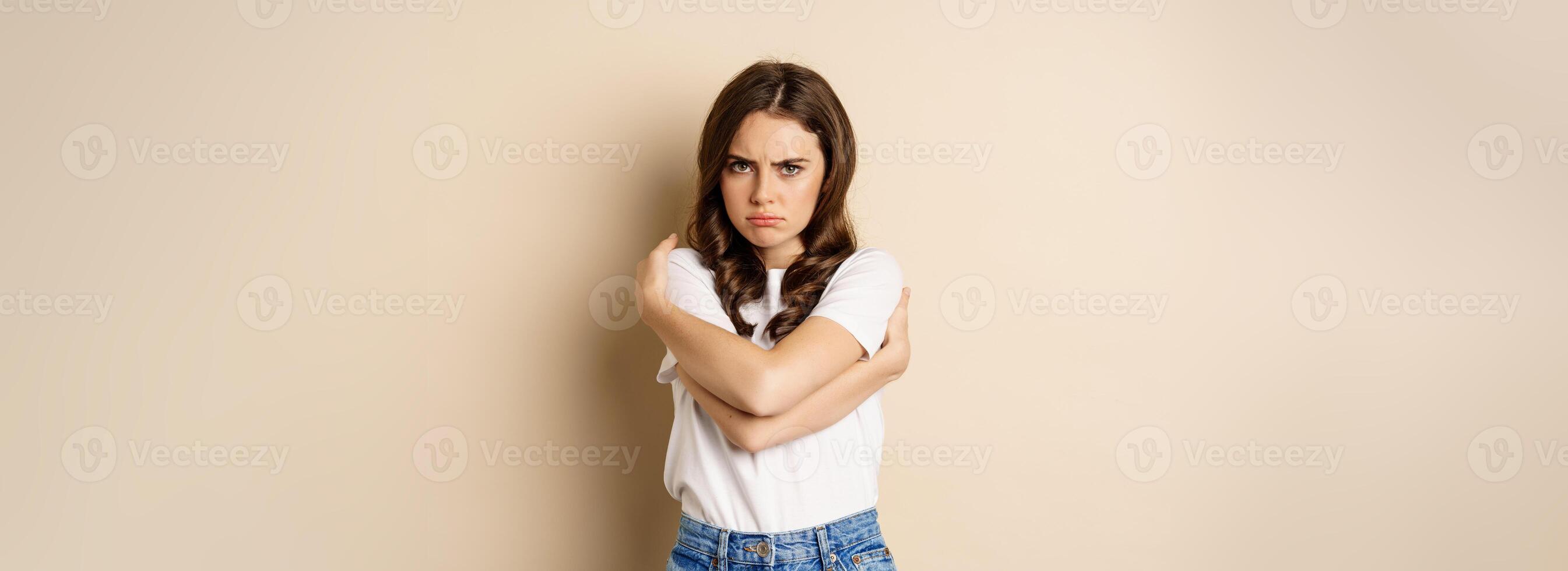 Offended angry woman cross hands on chest, frowning and sulking insulted, standing over beige background photo