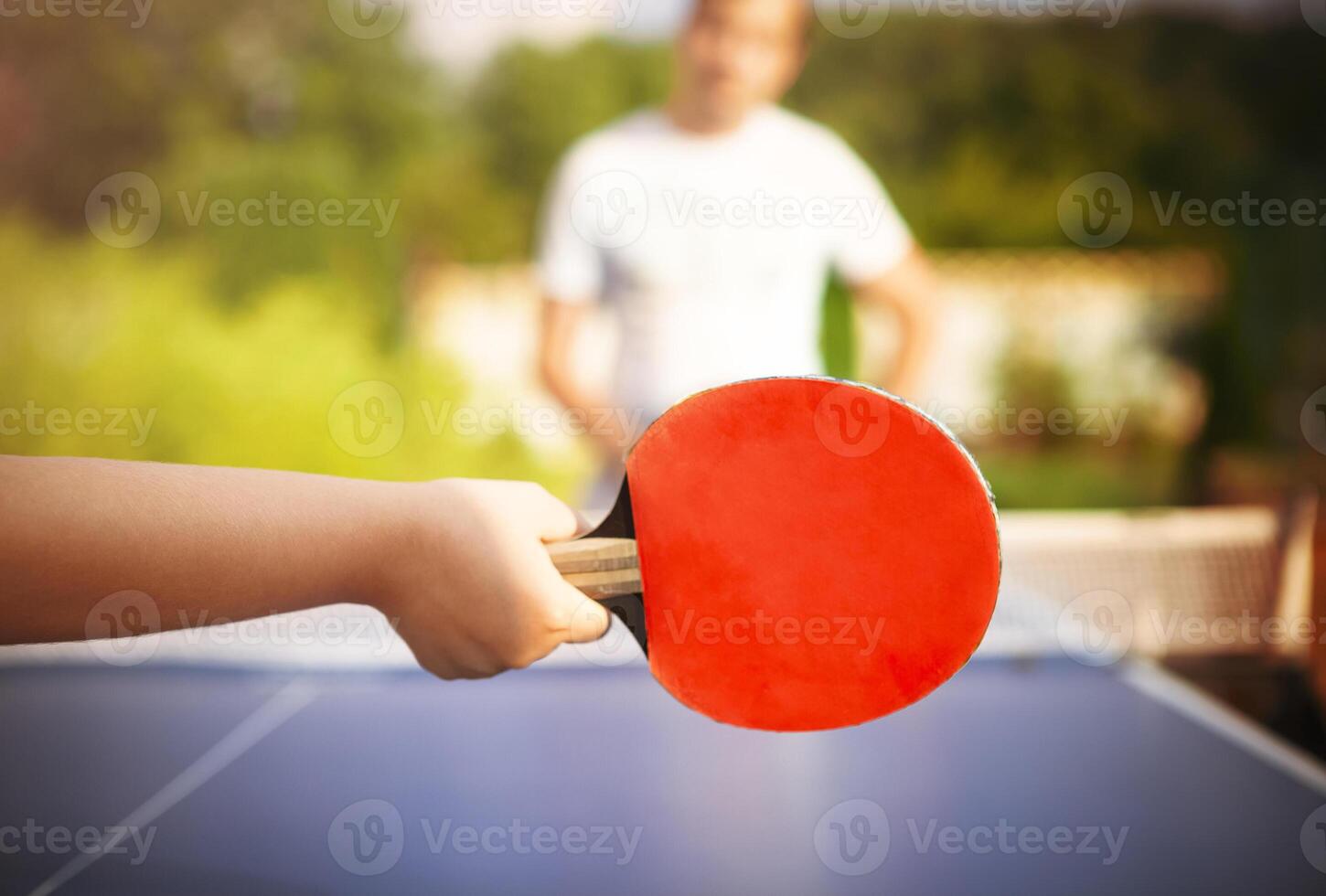 Unrecognizable child plying ping pong with father photo