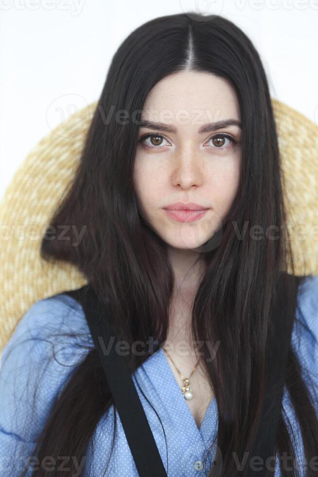 Beautiful woman in straw hat and blue shirt looking at camera photo