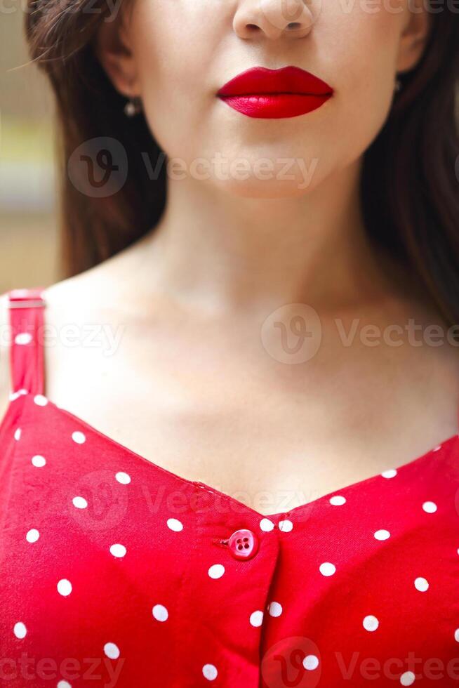 Smiling attractive girl in red polka dots dress in park photo