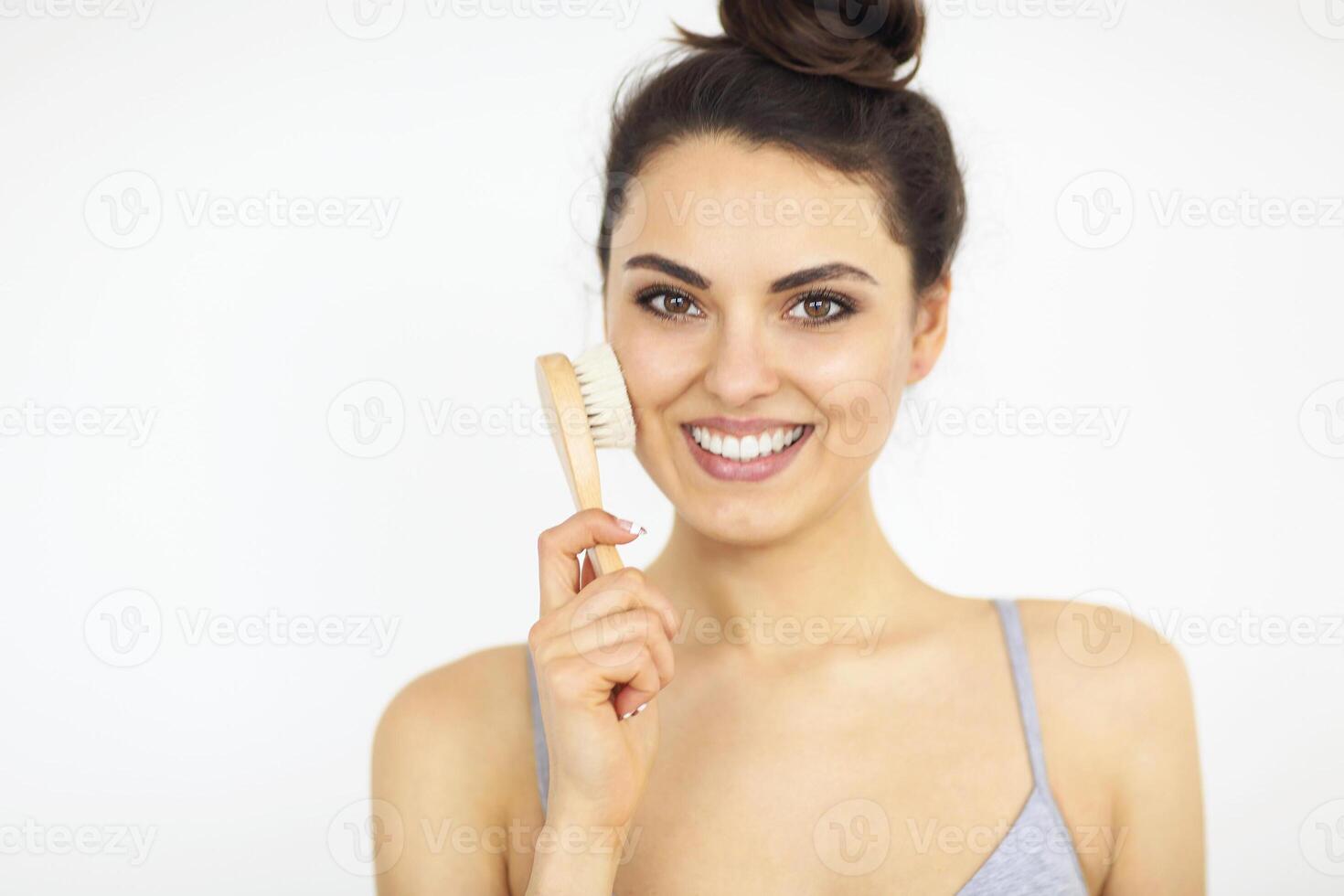 Portrait of cheerful beautiful attractive woman using wooden brush isolated on white background photo