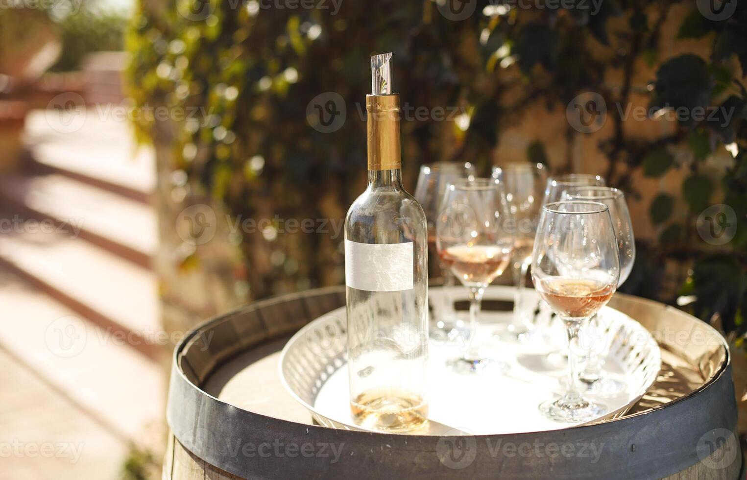 Many glasses and bottle of rose wine in the autumn vineyard photo
