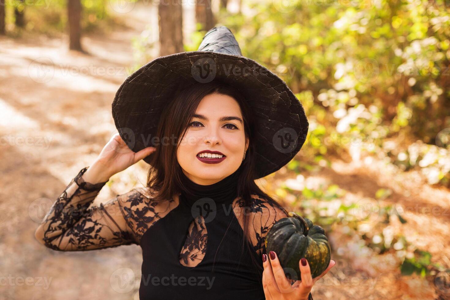 Young witch with jack o lantern in forest photo