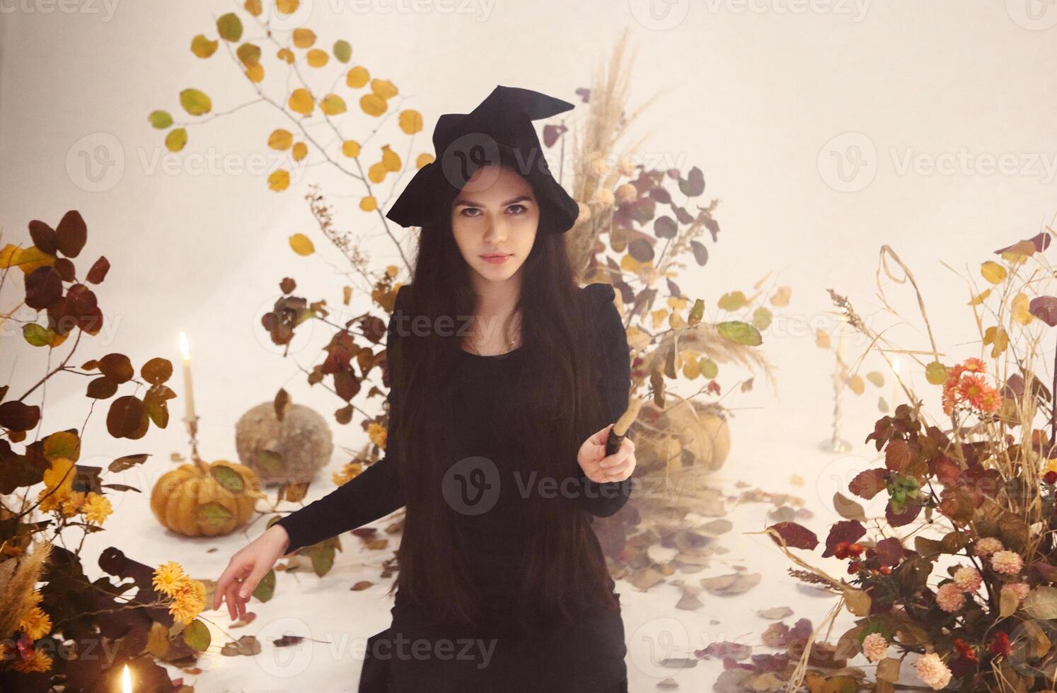 Young witch pointing wand at camera photo