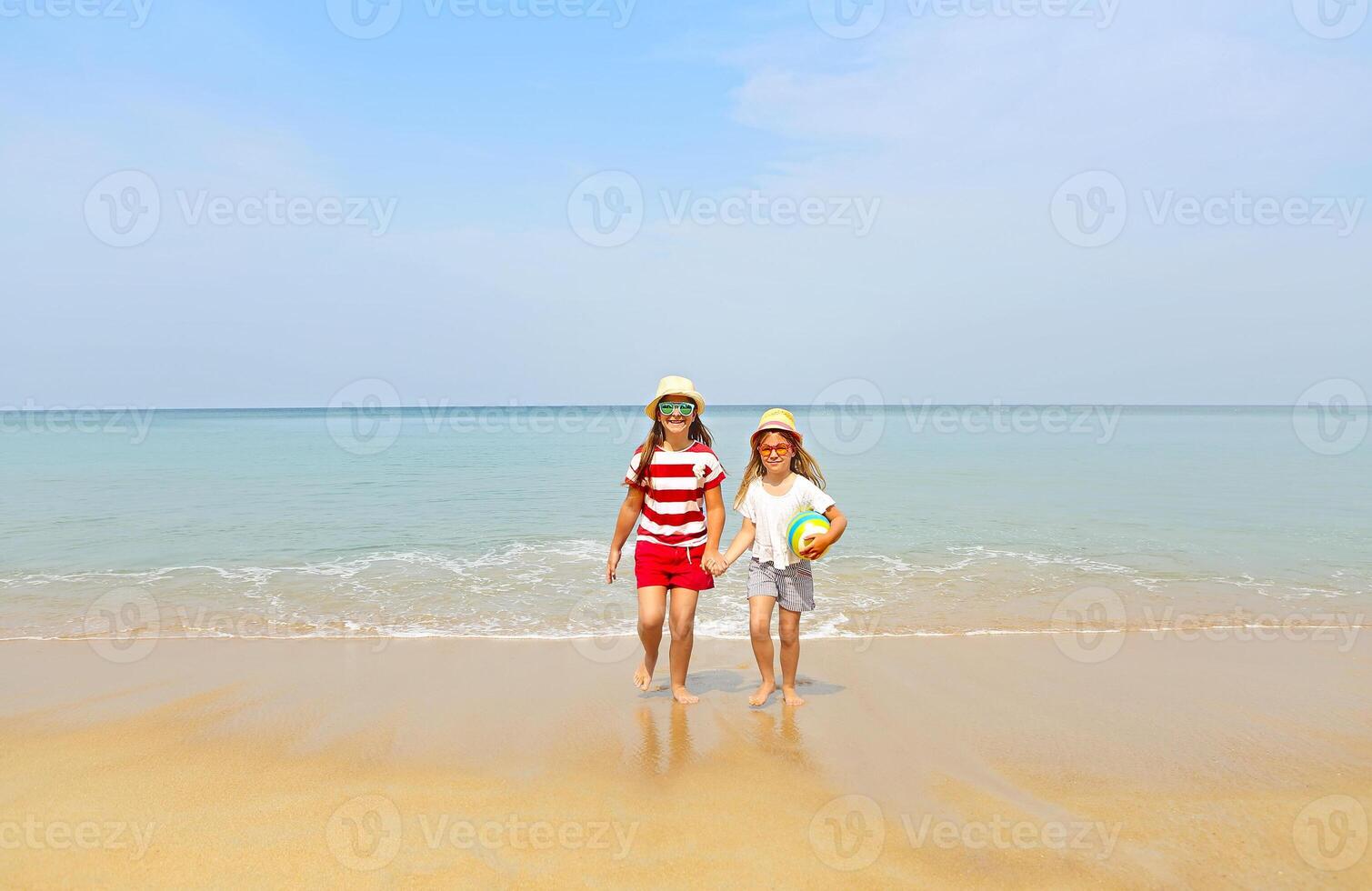 Happy sisters playing in sand on a beautiful beach photo