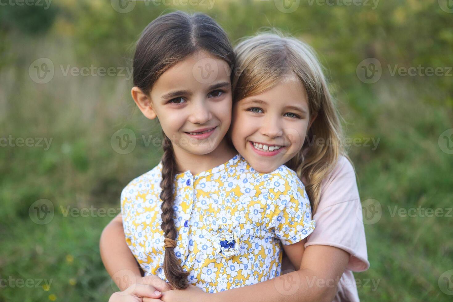 Portrait of the happy blond and dark haired girls sisters laughing and hug photo