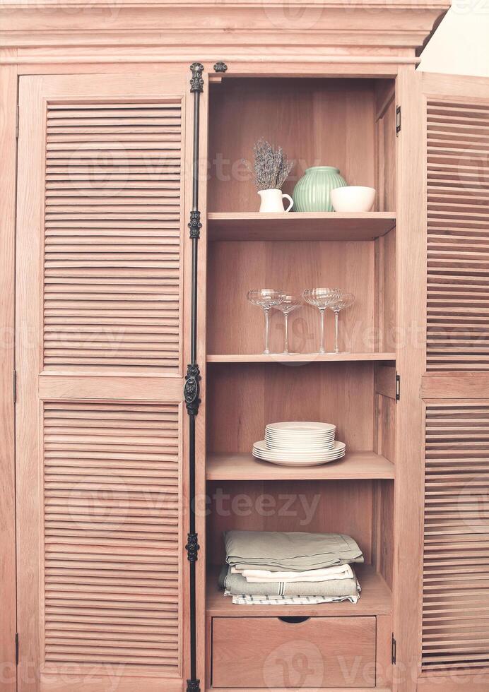 Kitchen cupboard with disheslike plates, tableclothes and glasses photo