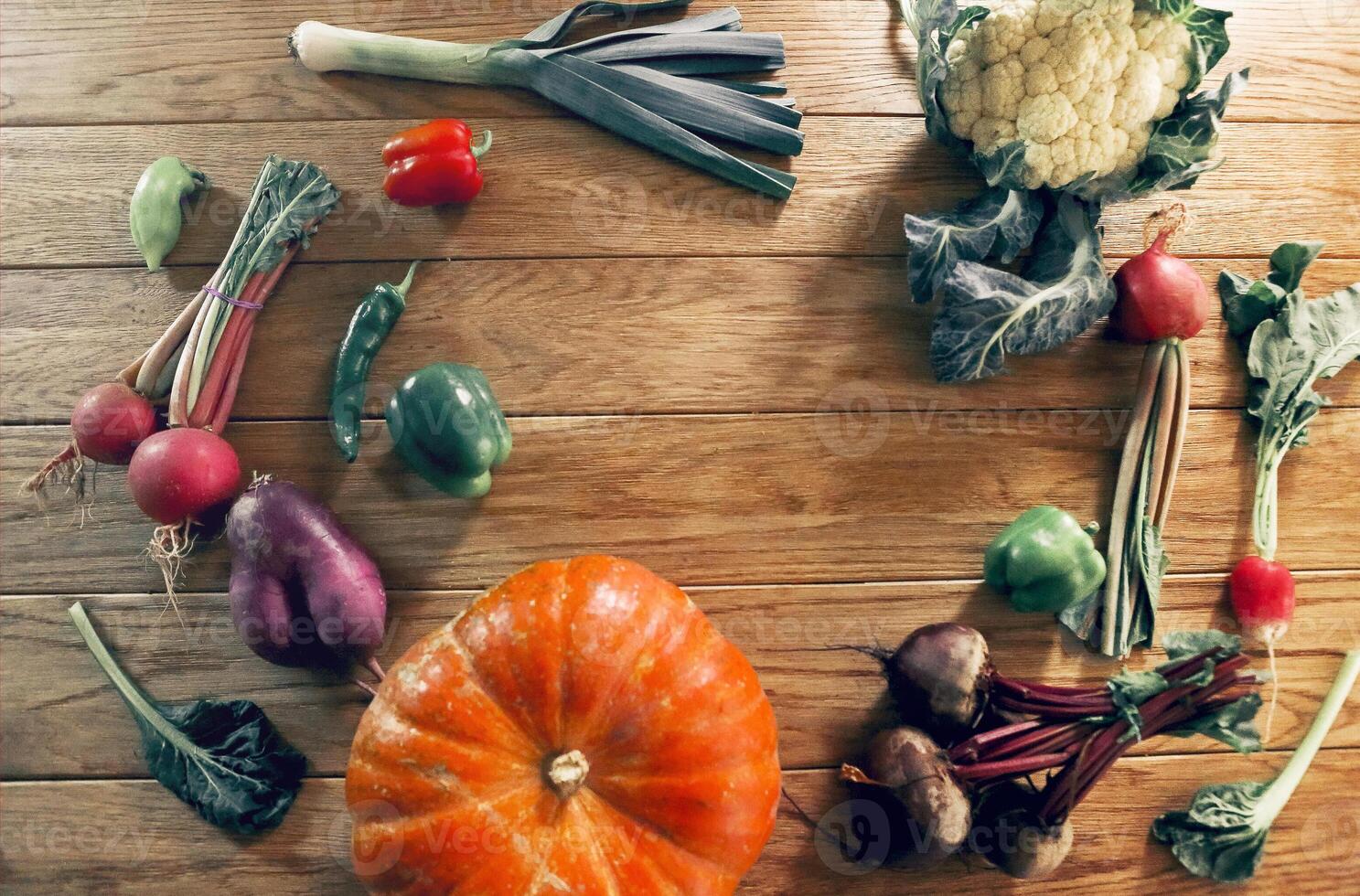 From above view of fresh organic vegetables laid out in circle on wooden table photo