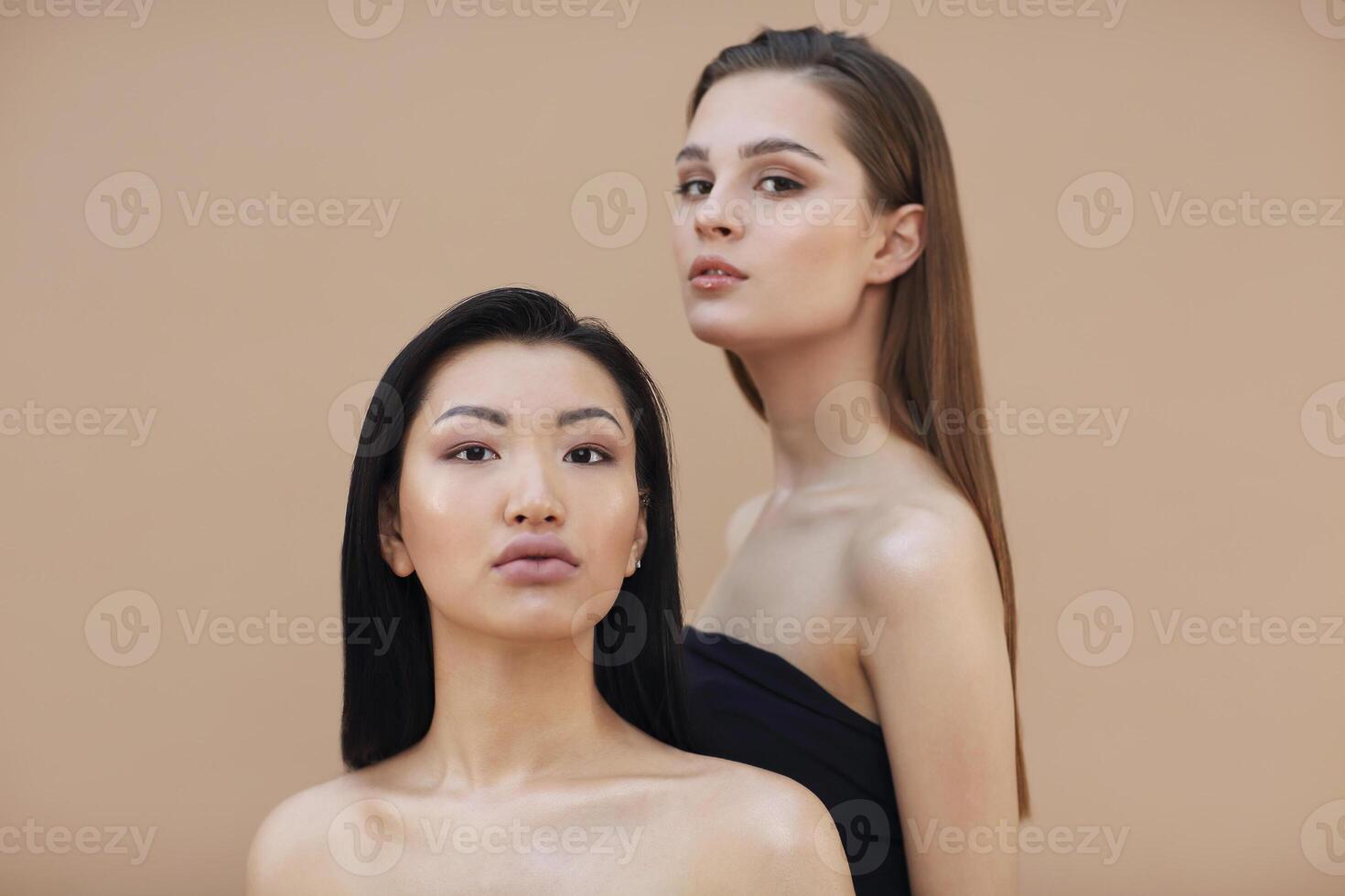 Two beautiful multicultural young women hugging while posing camera photo