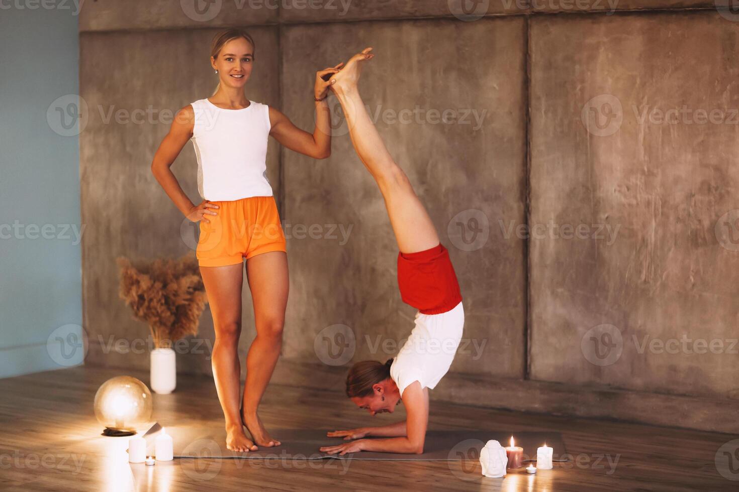 Two young slender women in colorful sportive wears doing yoga for relax, attractive females performing stretching exercise photo