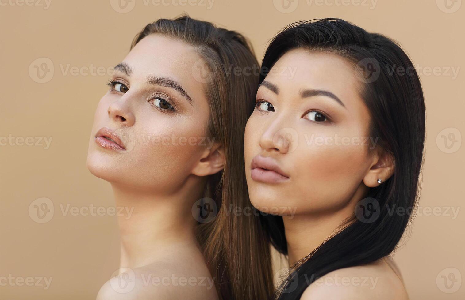 Two beautiful multicultural young women hugging while posing camera photo